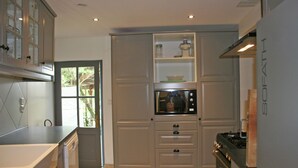 A modern kitchen with a built-in microwave, a stove, and a window with a view of greenery. - Holiday Home near Mont Ventoux Pool (Vaison-La-Romaine)