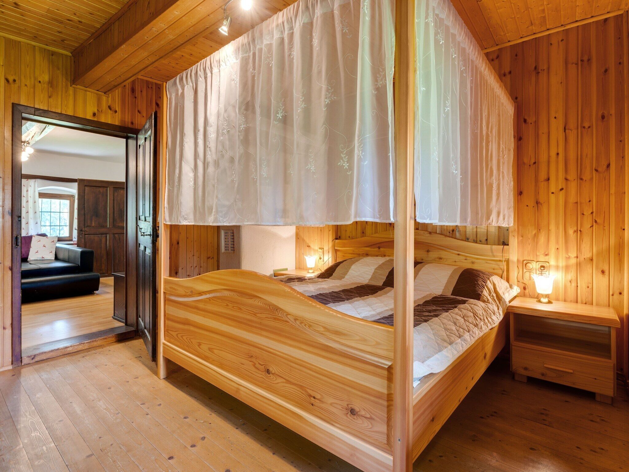Un lit à baldaquin en bois, avec une table de chevet et une petite table de nuit.