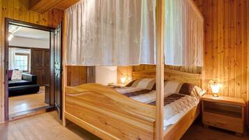 Un lit à baldaquin en bois, avec une table de chevet et une petite table de nuit.