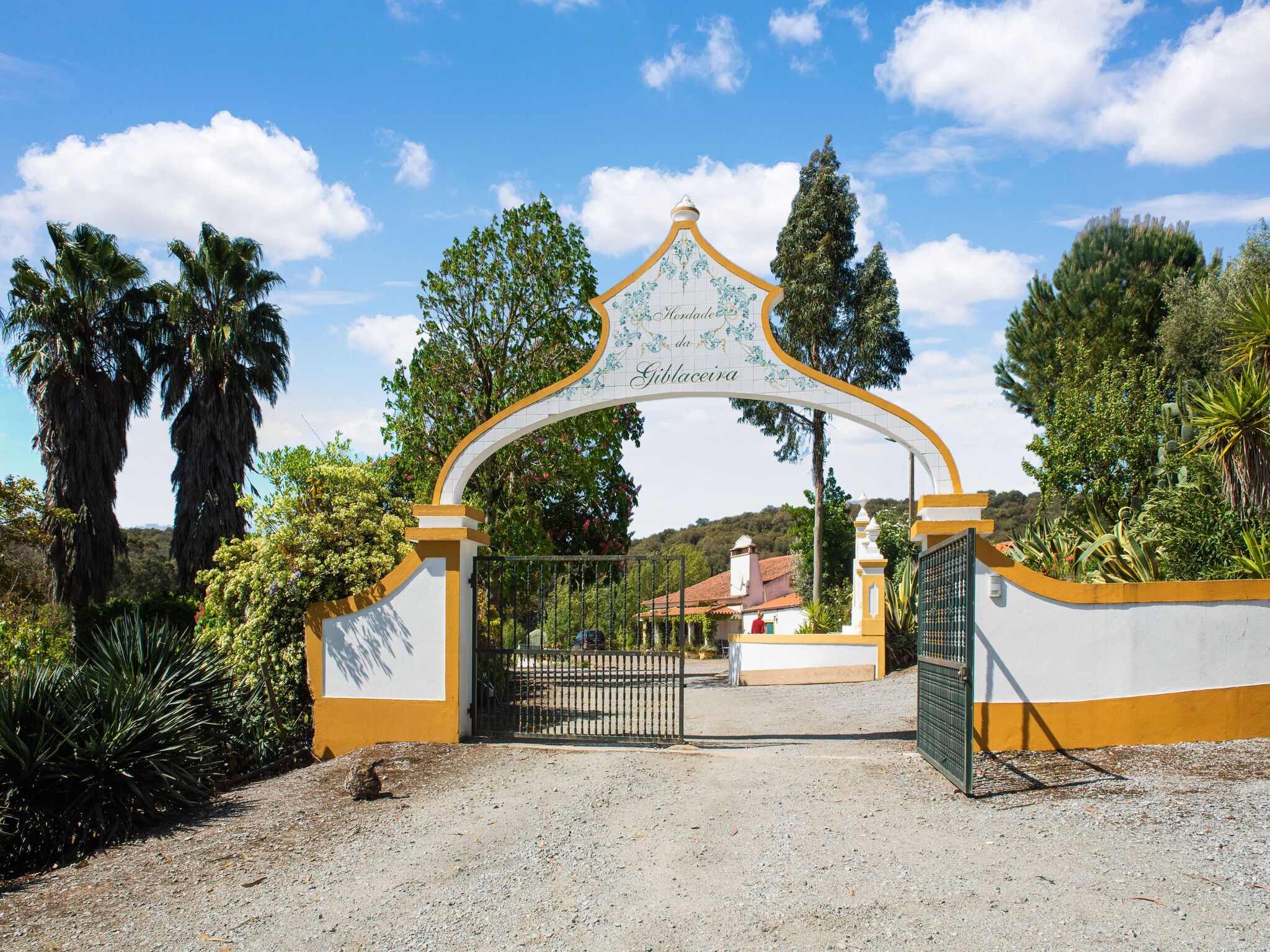 Uma entrada com portão, um arco decorativo e uma placa que diz 'Gibaceira'.