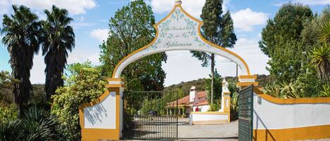 Uma entrada com portão, um arco decorativo e uma placa que diz 'Gibaceira'.