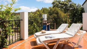 A terrace with two sun loungers, a small table, and a trash bin.
