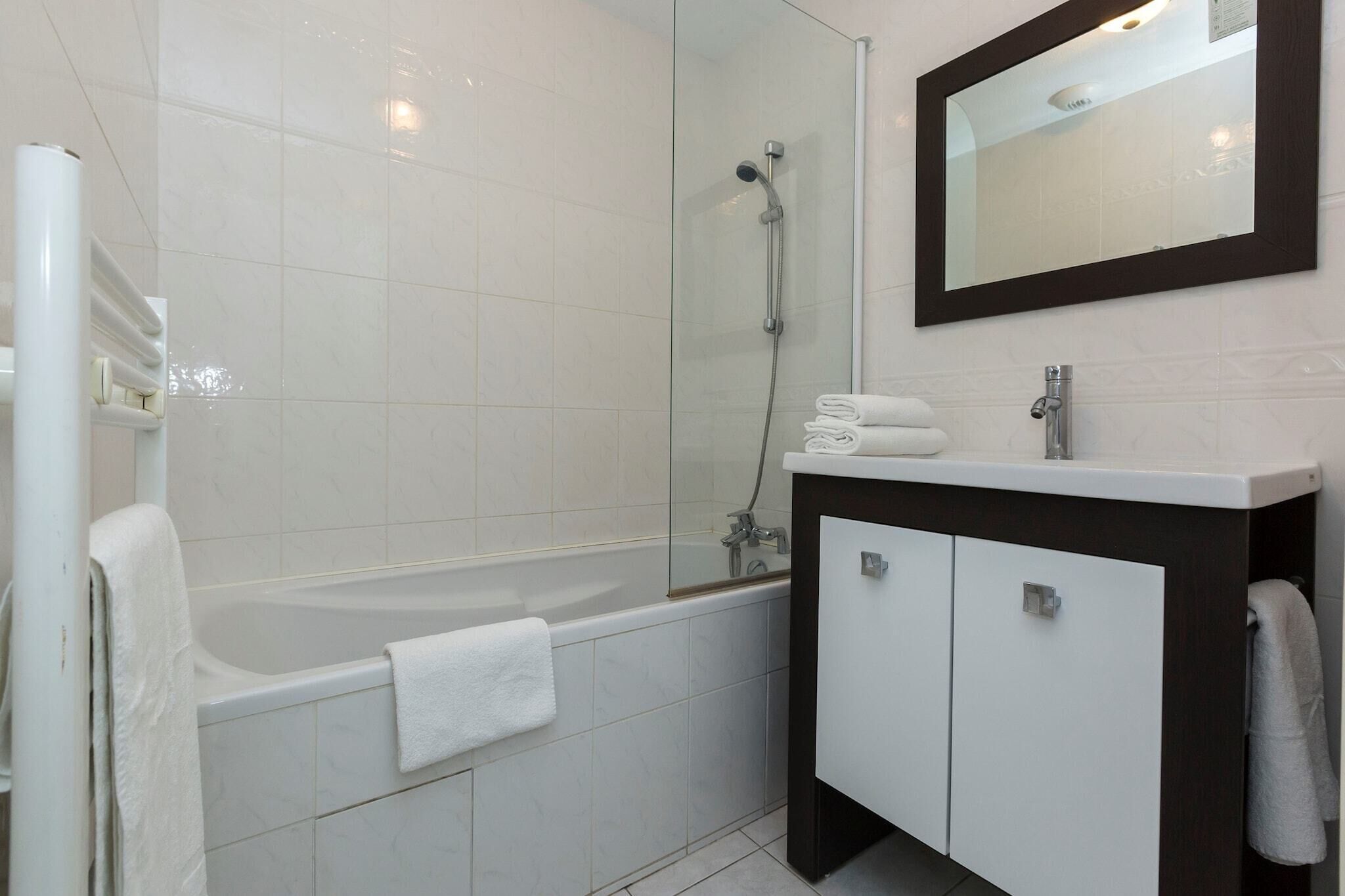 Een moderne badkamer met een badkuip, een douche met glazen wanden en een wastafelmeubel met spiegel.