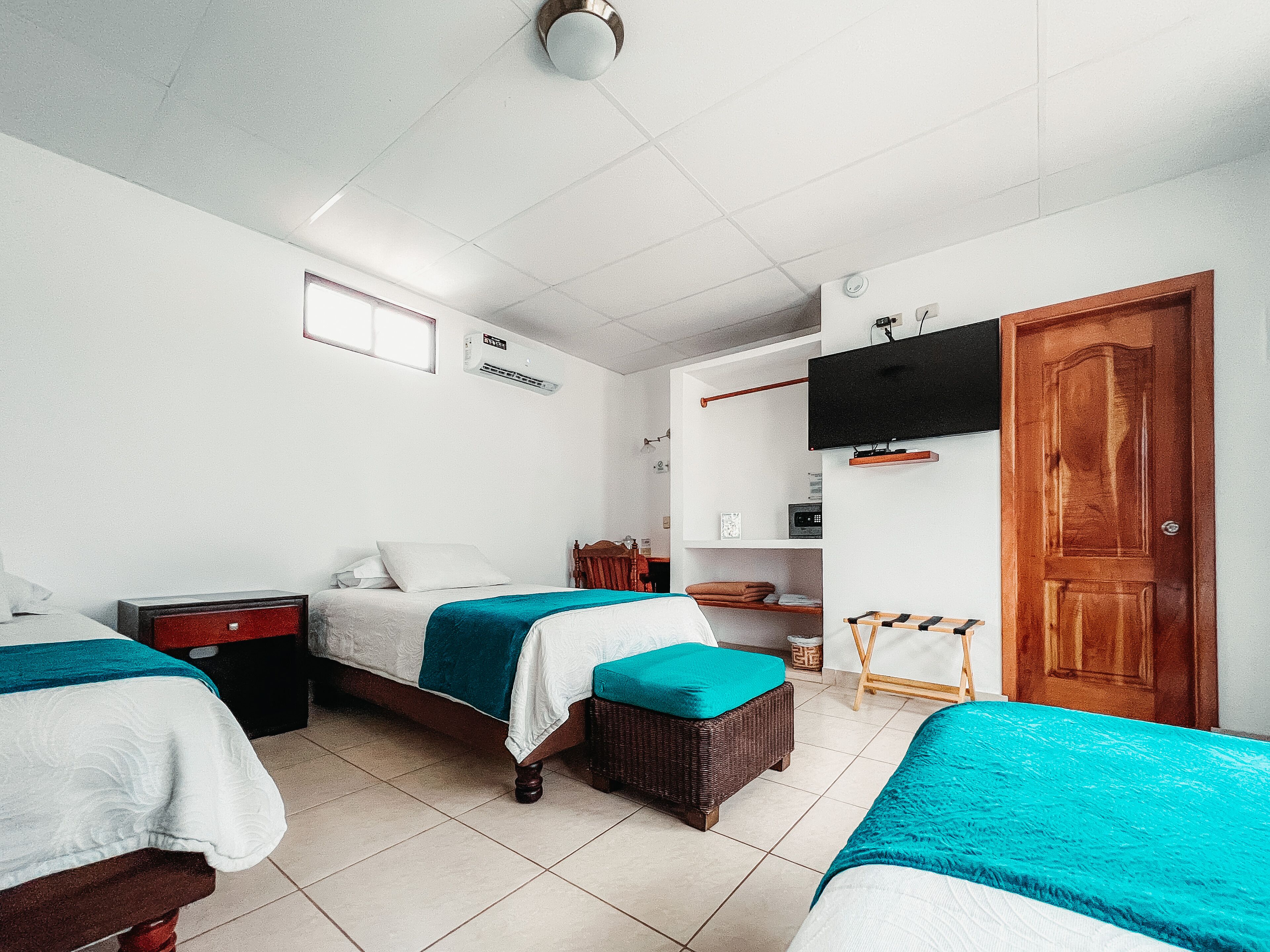 Habitación de hotel con dos camas, un televisor, una puerta de madera y una mesita.
