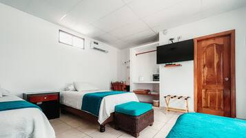 Habitación de hotel con dos camas, un televisor, una puerta de madera y una mesita.