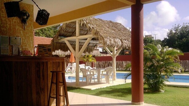 Ein überdachter Außenbereich mit Bar, Stühlen und Pool.