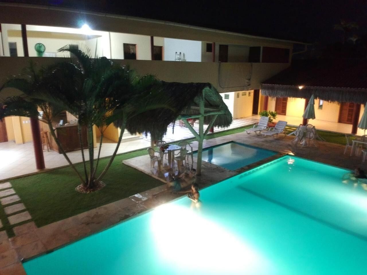 A swimming pool area with a water slide, palm trees, and lounge chairs.