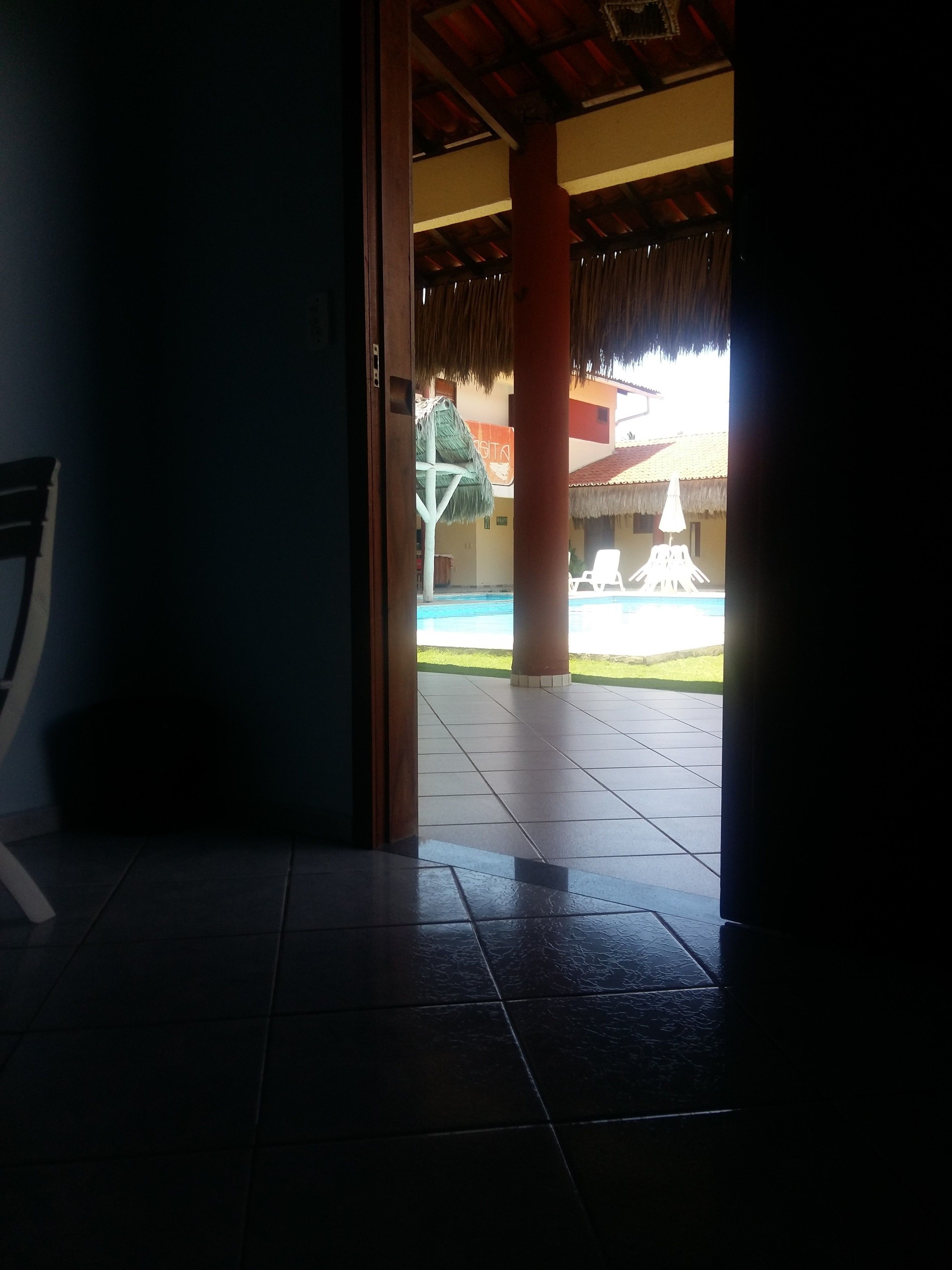 An indoor area with a tiled floor leading to an outdoor pool area.