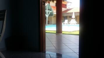 Un espacio interior con piso de baldosas que conduce a una zona de piscina al aire libre.