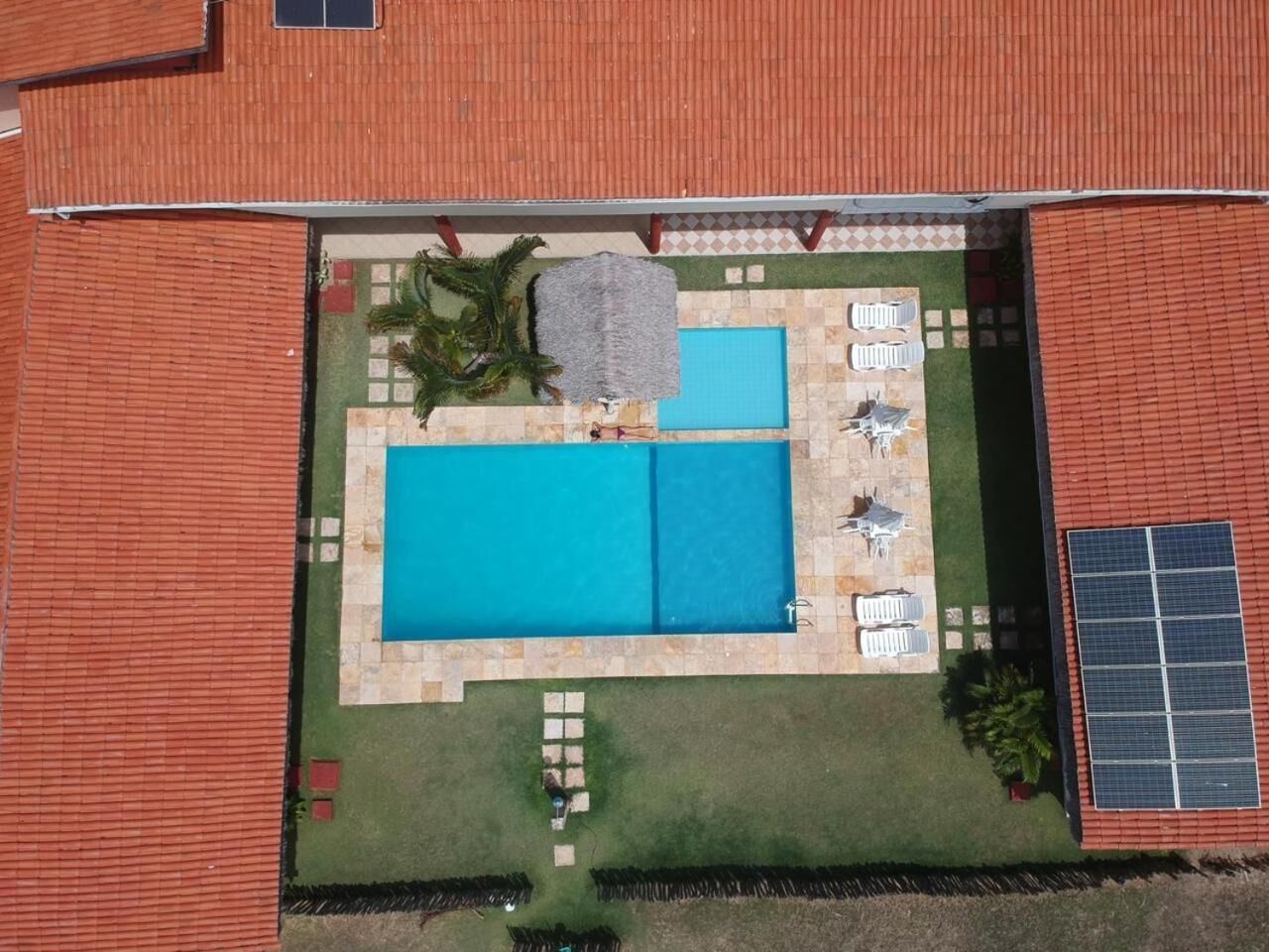 Vista aérea de un patio trasero con piscina, mobiliario de patio y paneles solares.
