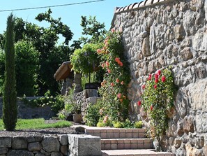 Steps lead to a serene gazebo amidst lush vegetation and a stone wall.