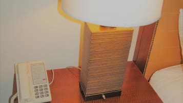 Een houten nachtkastje met een lamp en een telefoon.