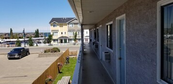 Un hotel con un espacio exterior cubierto, aparcamiento y vistas a una zona residencial con casas y un puerto deportivo.