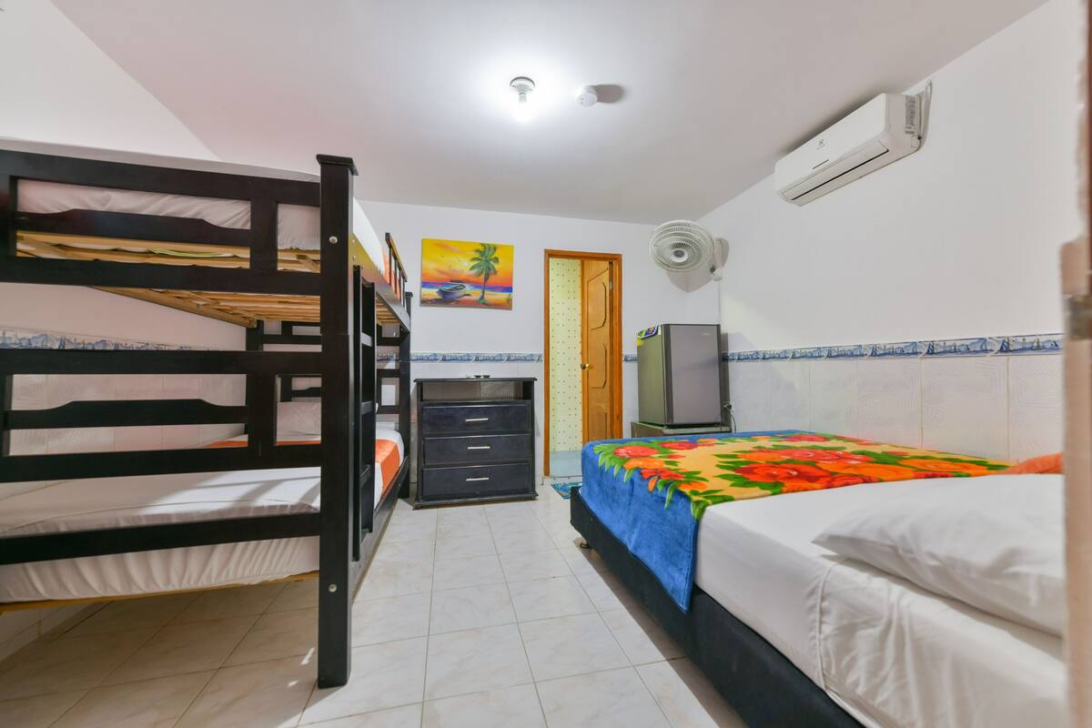 A room with bunk beds, a desk, a television, and a bed with a colorful blanket.