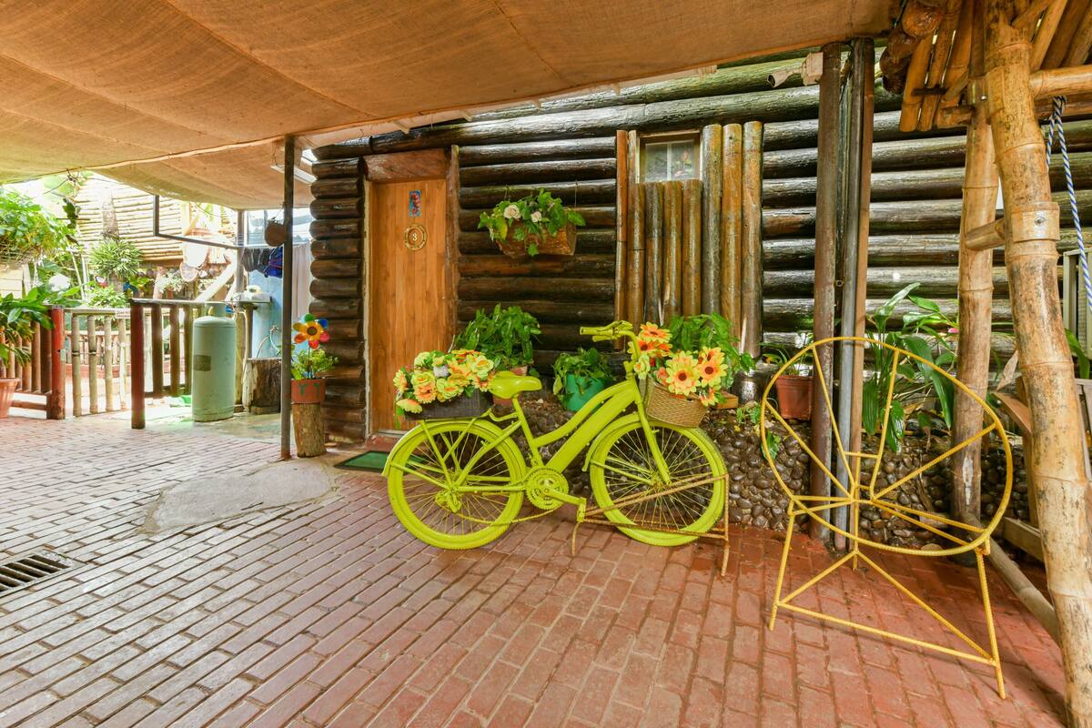 A rustic wooden cabin with a bicycle and flower baskets outside.