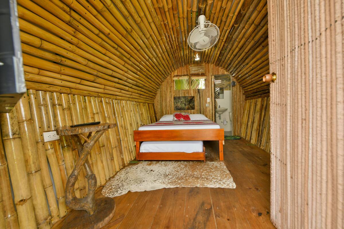 A room with a bed, a fan, and a wooden floor.