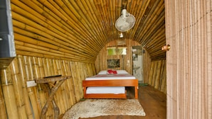 A room with a bed, a fan, and a wooden floor.