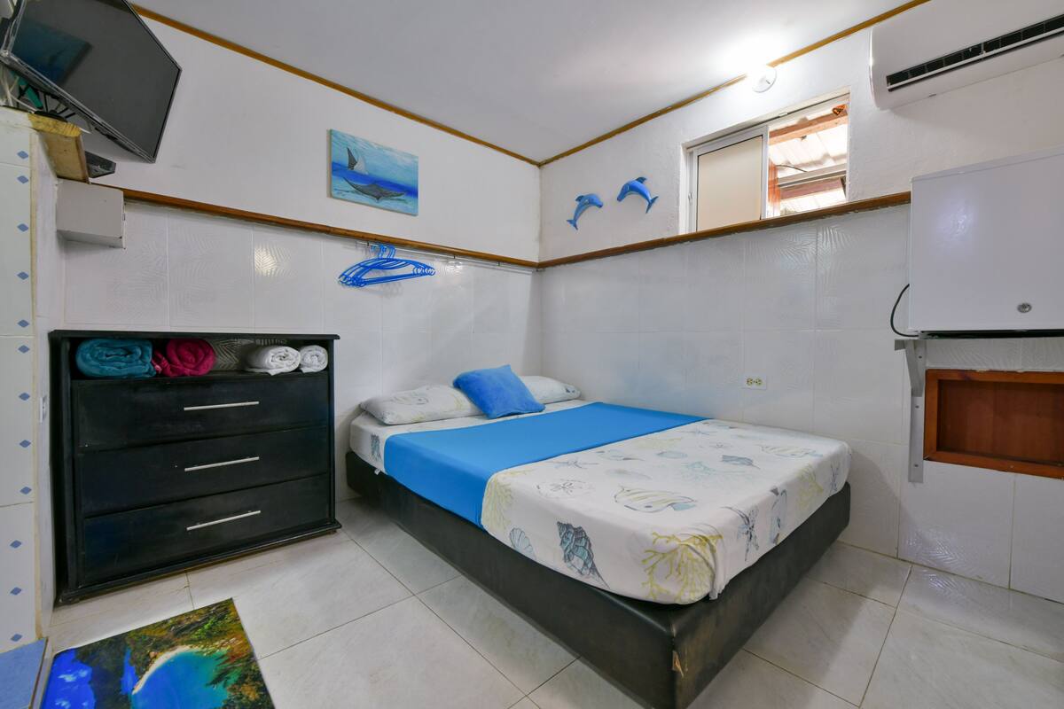A bedroom with a bed, a dresser, a television, and a window.