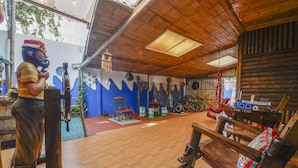 A rustic interior with a wooden ceiling, a large chair, and a statue.