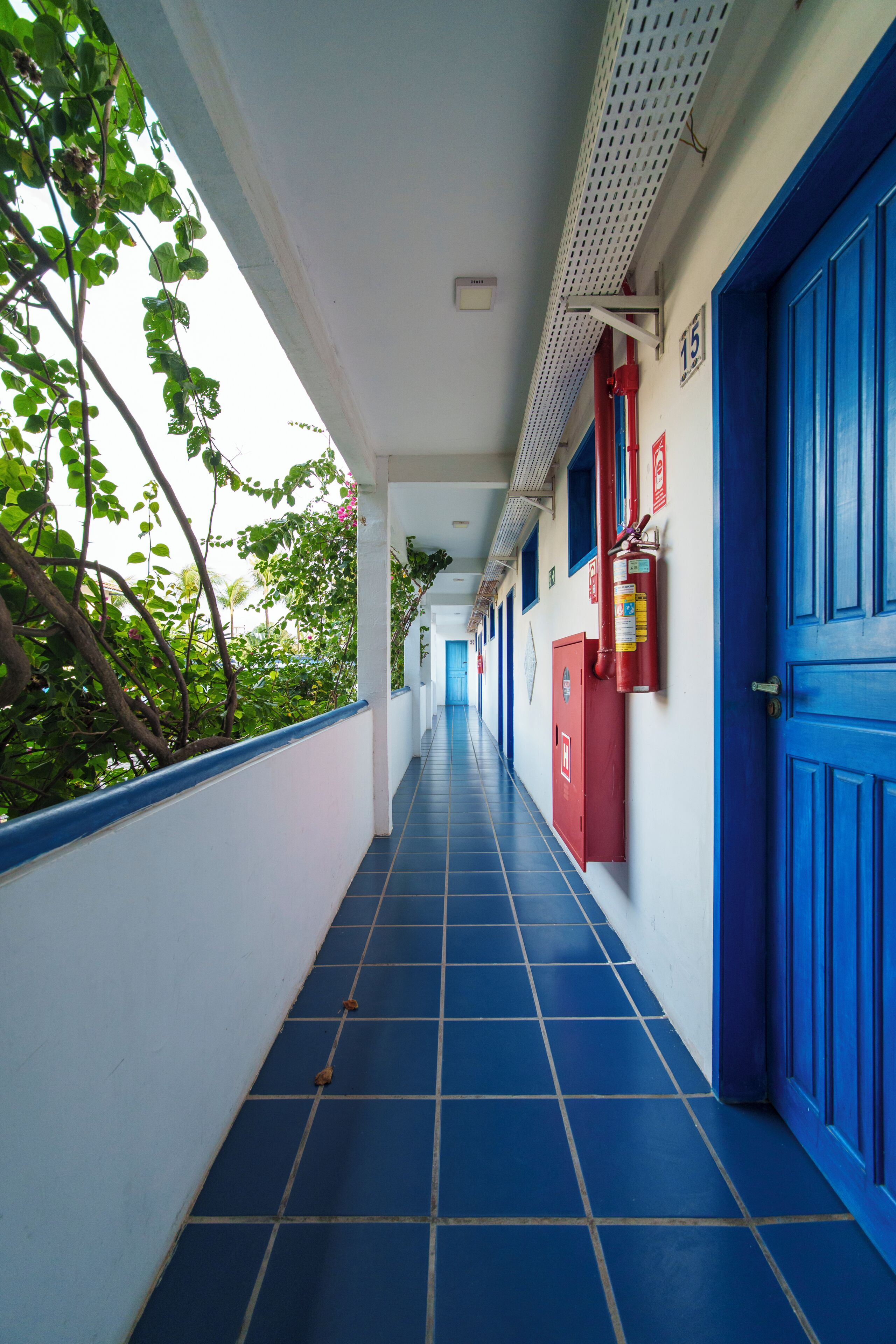 A corridor with blue doors, a fire extinguisher, and a number 15 sign.