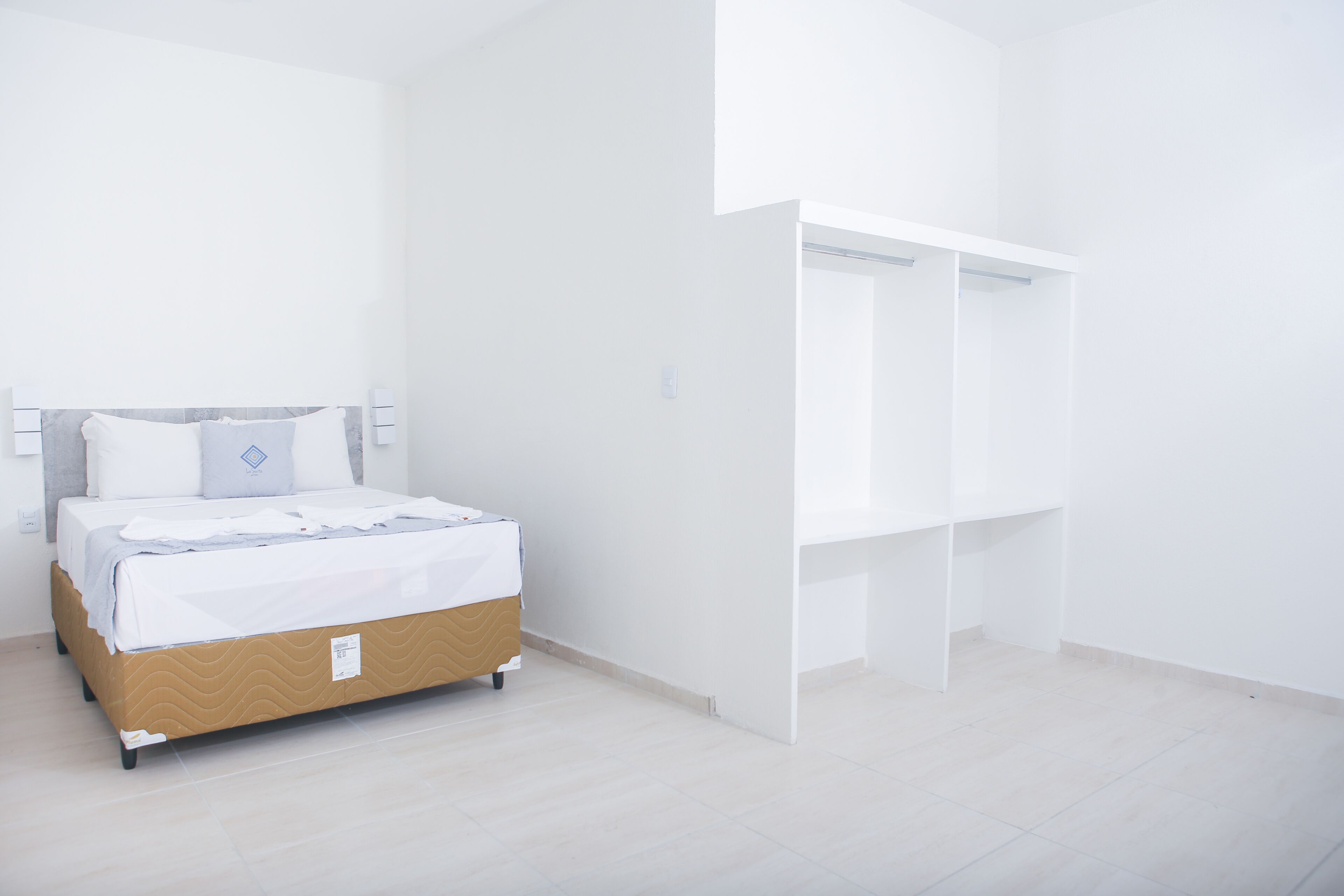 Quarto com cama, guarda-roupa branco e parede branca.