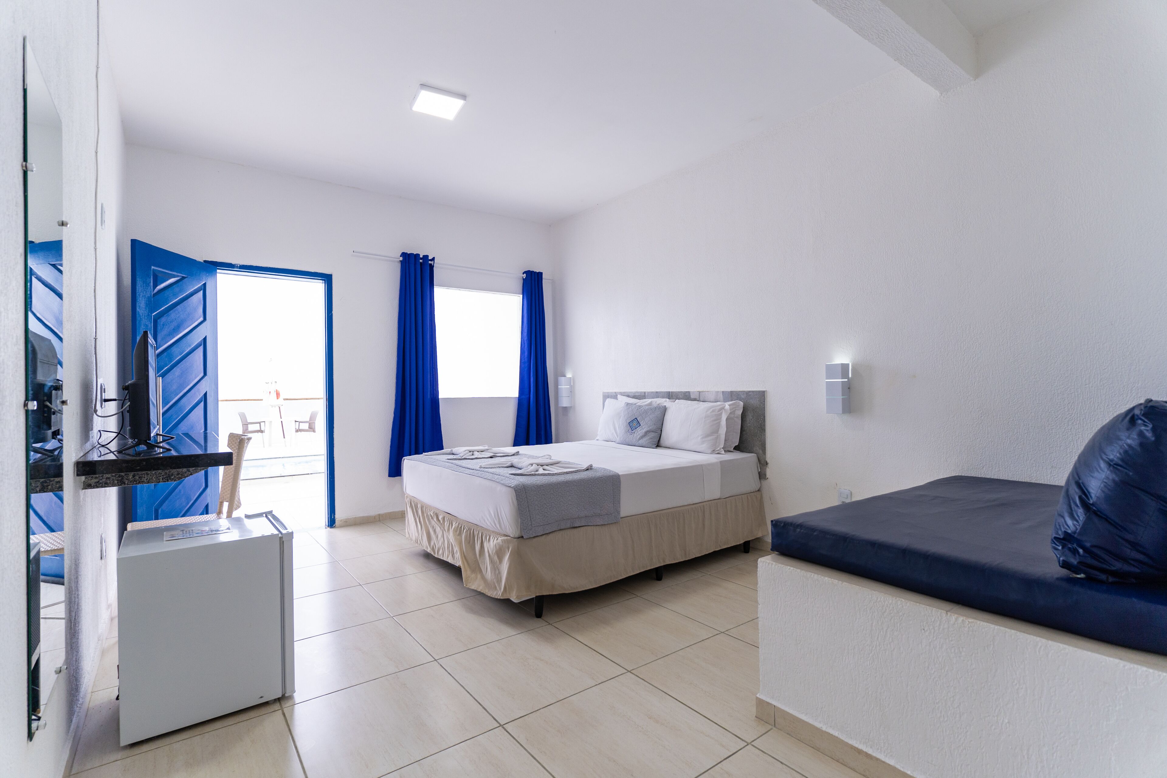 Un dormitorio con una cama, un escritorio y un refrigerador pequeño.