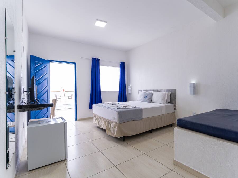 A bedroom with a bed, a desk, and a small refrigerator.