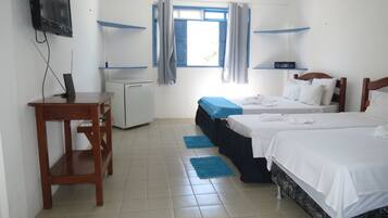 A hotel room with two beds, a desk, a small refrigerator, and a television mounted on the wall.
