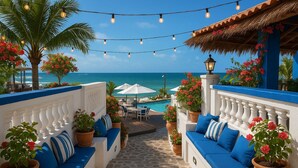 A sunlit outdoor seating area with a view of the ocean, string lights, and potted plants. - La Suite Praia Hotel (Caucaia)