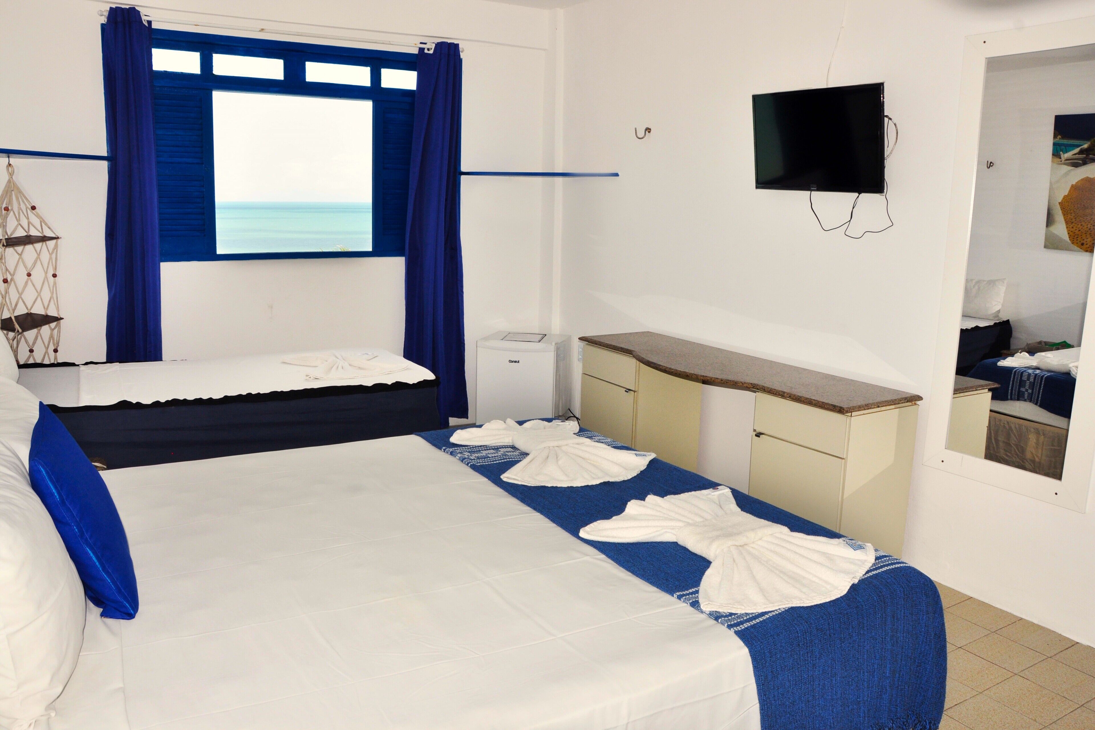 Una habitación de hotel con una cama, un escritorio, un televisor y una ventana con cortinas.