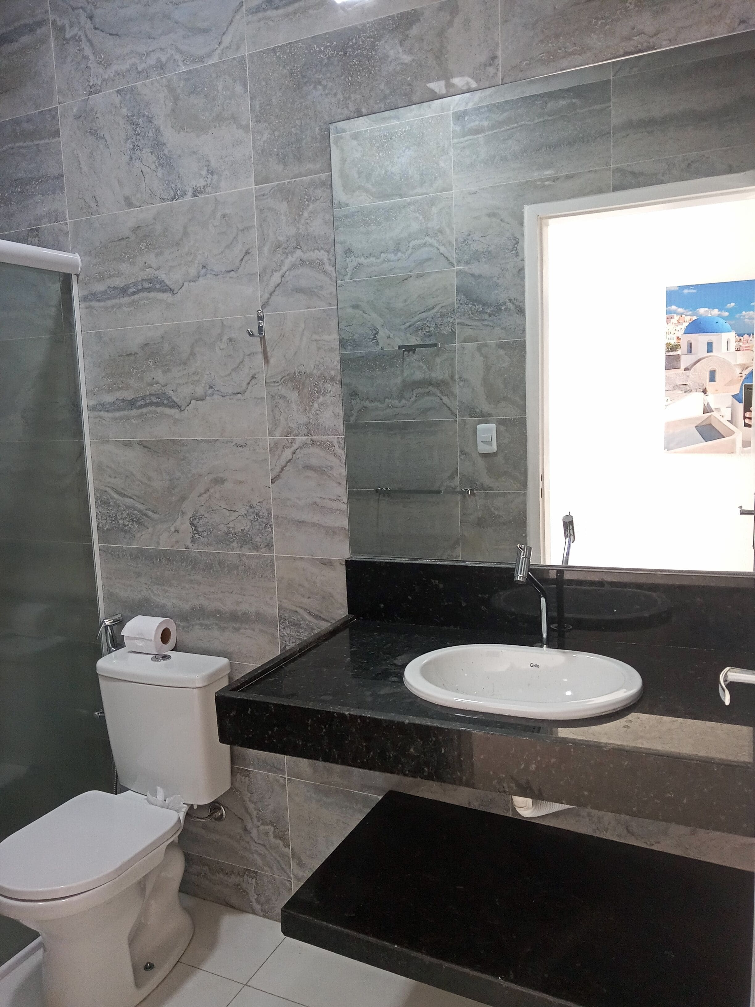 A bathroom with a toilet, sink, and mirror.