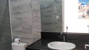 A bathroom with a toilet, sink, and mirror.