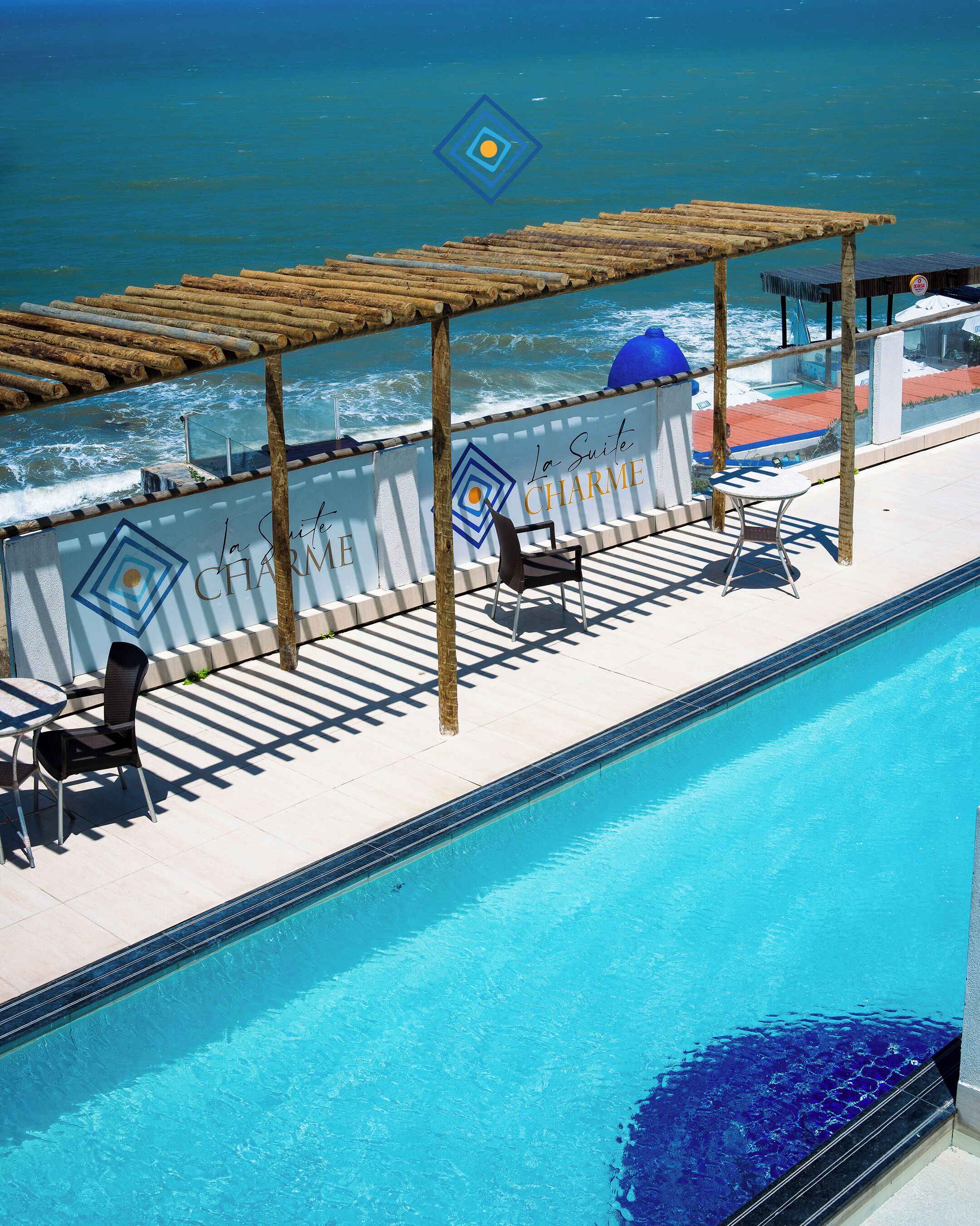 A poolside area with a view of the ocean, a pergola, and a lounge chair.