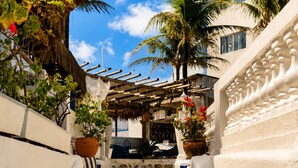 A stone staircase leading up to a building with a thatched roof and potted plants. - La Suite Praia Hotel (Caucaia)