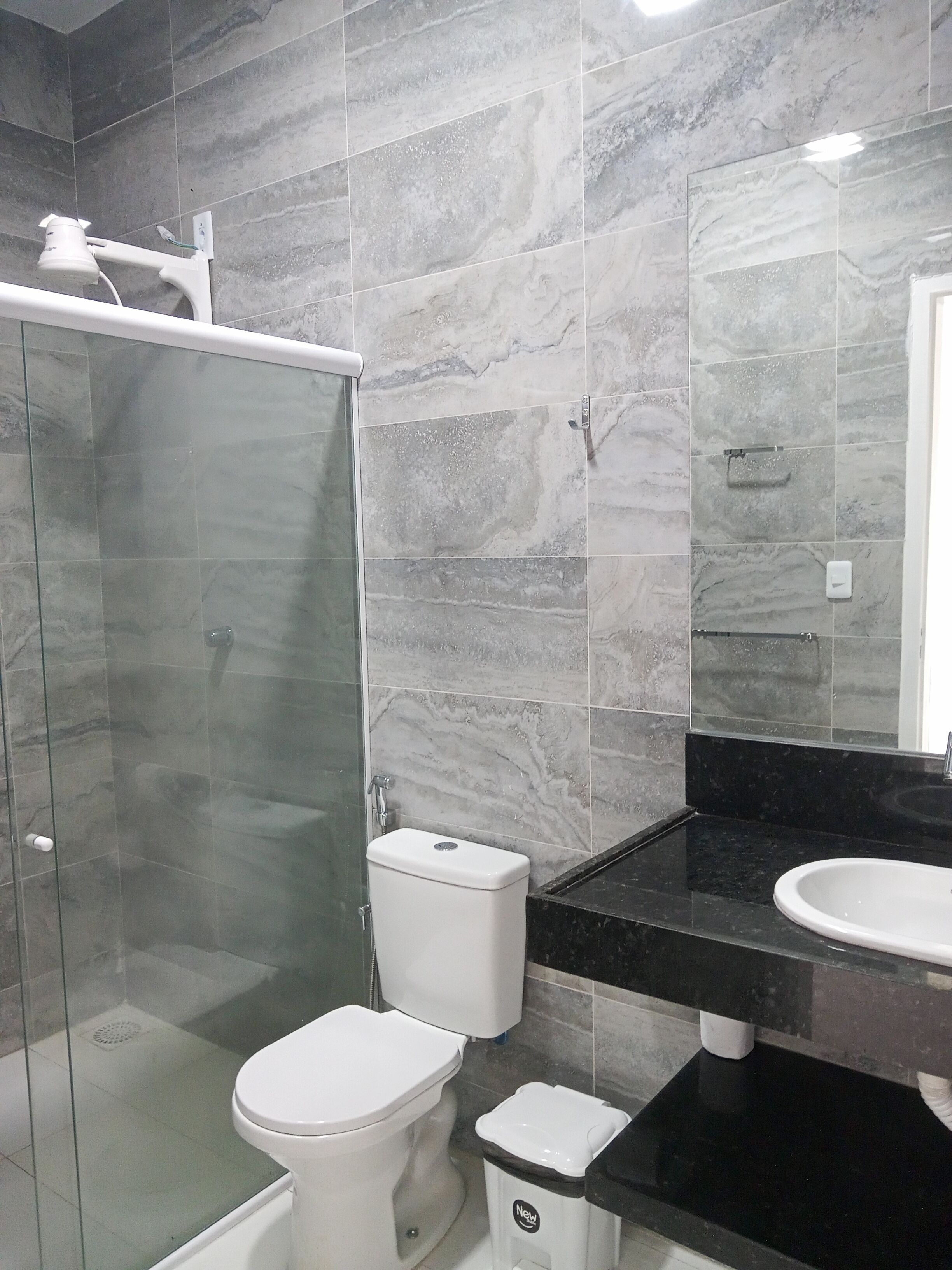 Une salle de bain avec une douche à parois de verre, des toilettes, un lavabo et un miroir.