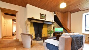 A cozy living room with a fireplace, a sofa, a television, and a staircase leading to another room.