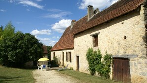 A stone building with a gravel path leading to a table and chairs.