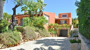 A courtyard with a cobblestone path, a stone wall, and a building with a tiled roof.