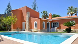 A swimming pool with a stone wall and a building with arched windows and a stone chimney.