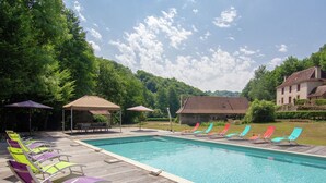 Une piscine entourée de chaises longues colorées et d’une terrasse en bois.