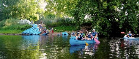 A group of people in kayaks on a calm river surrounded by lush greenery.