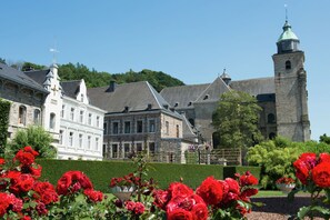 A historic building with a prominent tower and a large white structure with multiple windows. - Malmedy Hillside Spa Retreat (Malmedy)