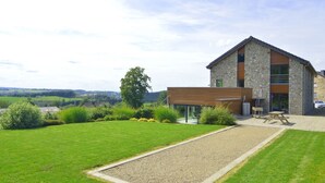 A modern house with a stone facade, a wooden extension, and a well-maintained lawn.
