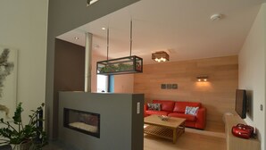 A modern living room with a fireplace, a red sofa, a coffee table, and a television mounted on the wall.