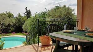 A patio with a pool, chairs, and a table set for dining.