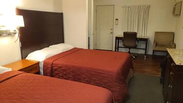 A hotel room with two beds, a desk, a chair, and a dresser.