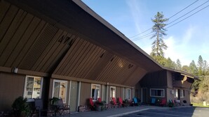Un motel con techo inclinado, varias ventanas y una zona de estar al aire libre con sillas.