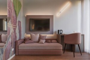 En moderne stue med sofa, et fladskærms-tv på væggen, et sofabord med lampe og en lænestol.