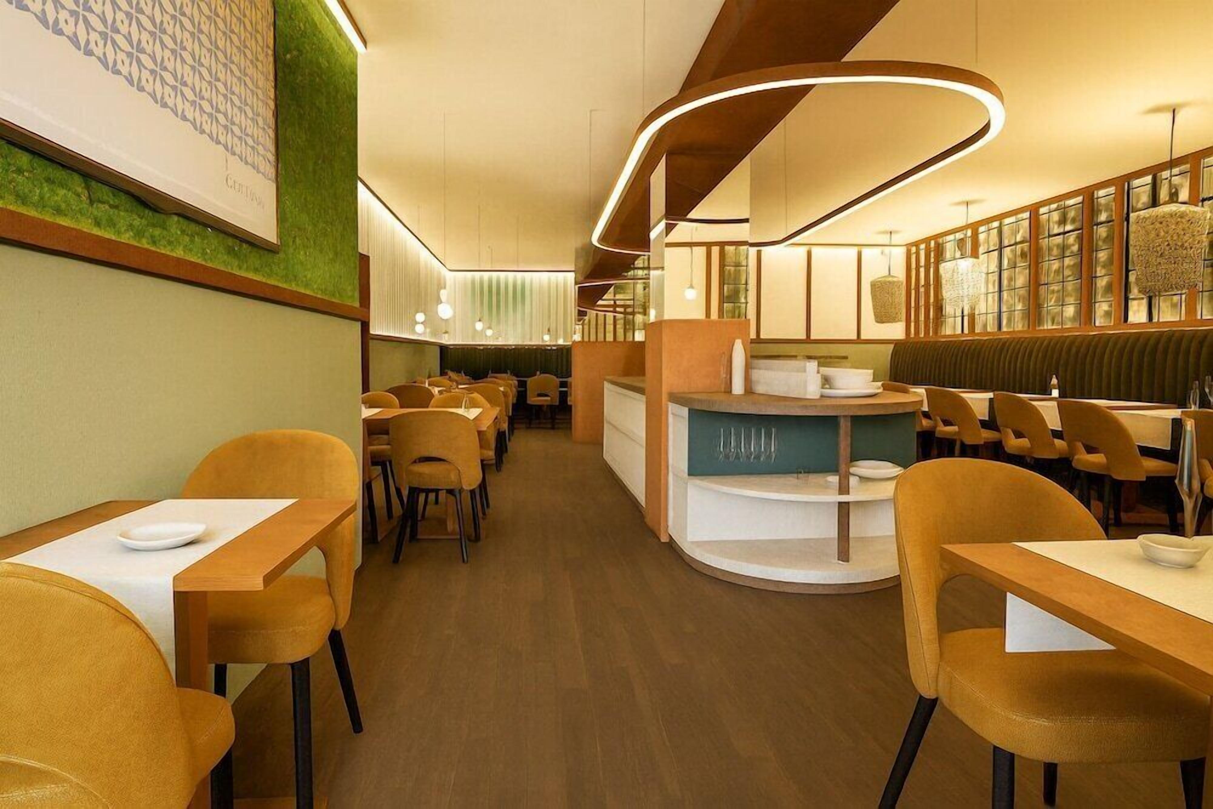 A restaurant with wooden tables and chairs, a counter, and a green wall with a patterned design.