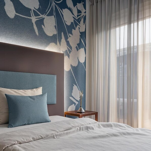 A hotel room with a bed, a nightstand, a vase with a plant, and sheer curtains. - Hotel Castello (L'Aquila)